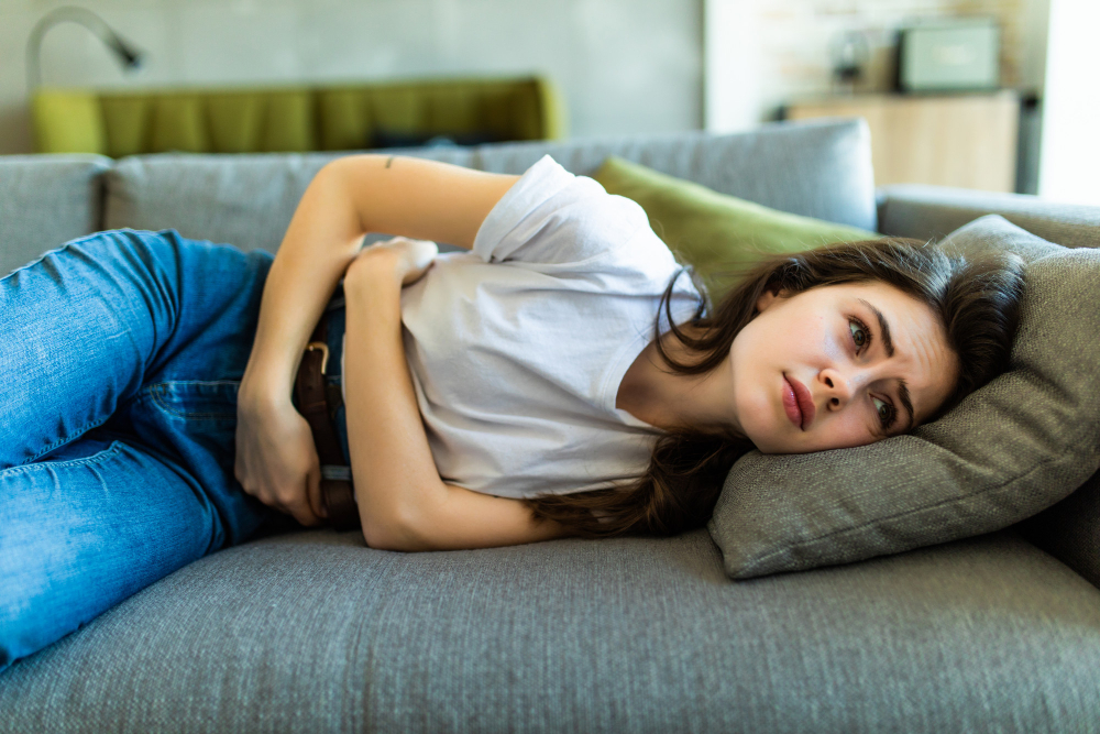 Femeie întinsă pe canapea cu dureri abdominale