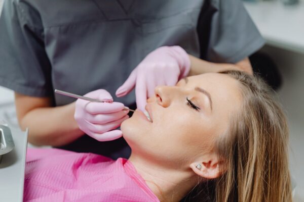 Pacientă la consultație stomatologică cu dentist folosind instrumente dentare